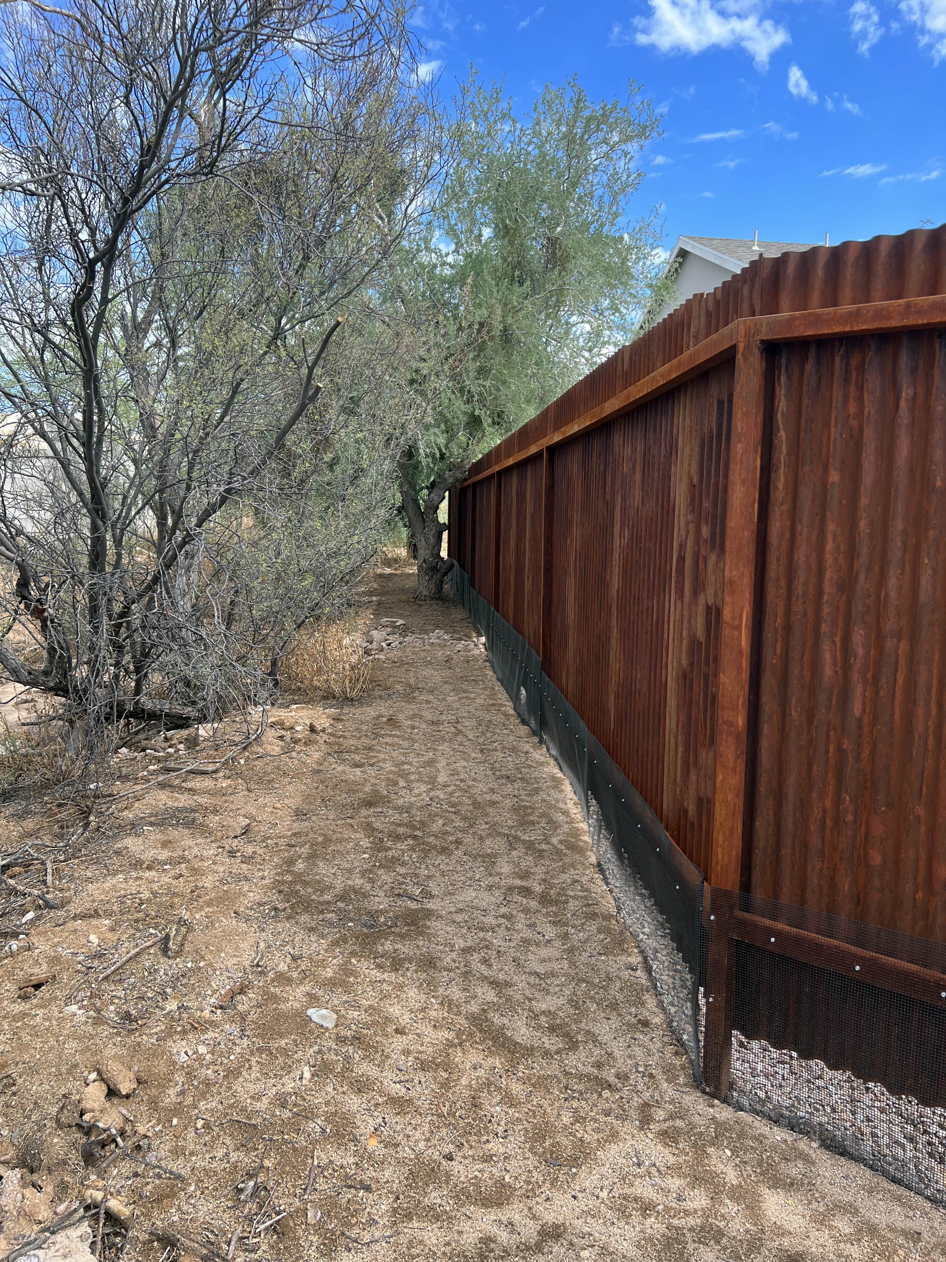 Low black mesh transition along a corrugated metal fence