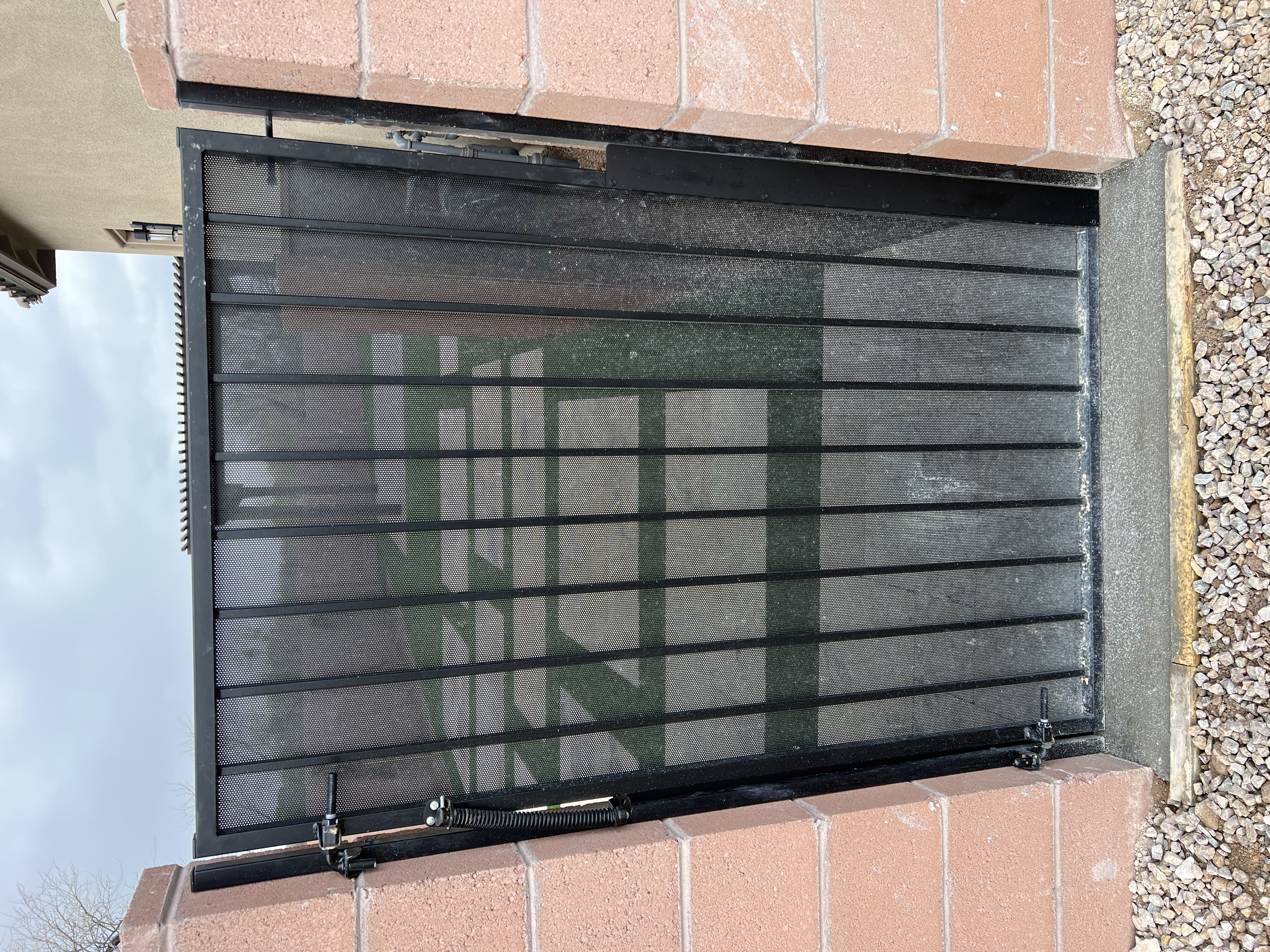 Black metal gate with fine barrier mesh fitted within its frame