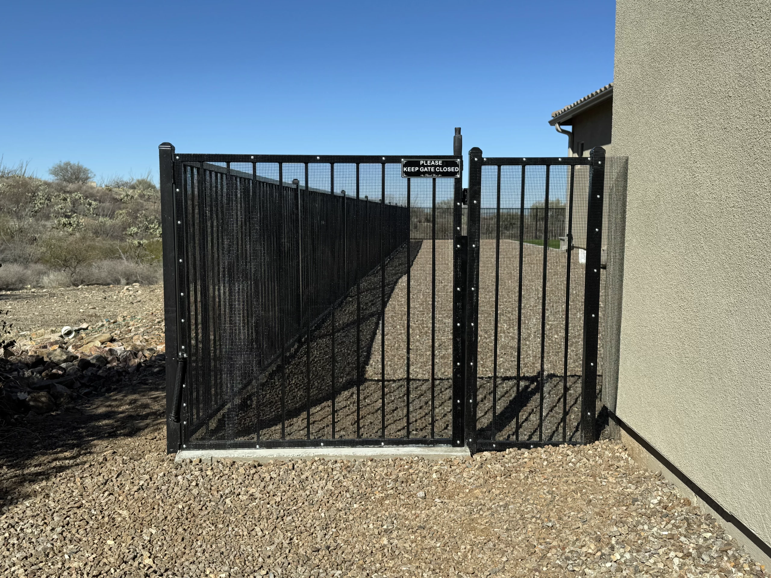 Residential yard with black mesh fitted to view fencing and a gate